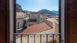 A view from a balcony with a tiled roof, overlooking a coastal town with terracotta-roofed buildings and a mountain in the background. - Terrazza Mandralisca by Wonderful Italy (Cefalù)