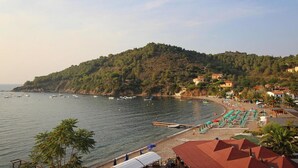 A coastal view with a beach, boats, and a hill with buildings. - Apartment in Elba near Pebble Beach (Rio nell'Elba)