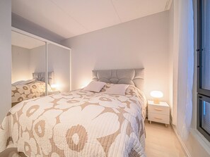 A bedroom with a bed, a bedside table, a nightstand, a mirror, and a window. - Villa valoki by Interhome (Kittilä)