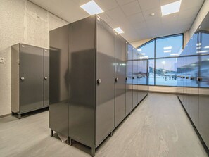 A modern interior with metal lockers, a concrete floor, and a large window offering a view of a snowy landscape.