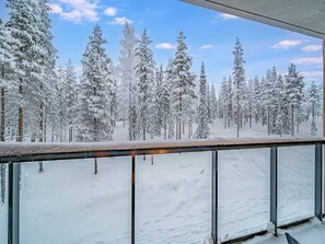 A snowy forest view from a balcony with metal railings. - Villa valoki by Interhome (Kittilä)