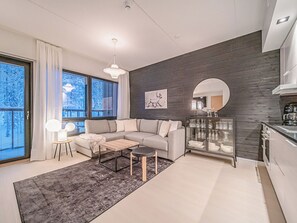 A modern living room with a sectional sofa, a coffee table, and a dining area with a glass cabinet.