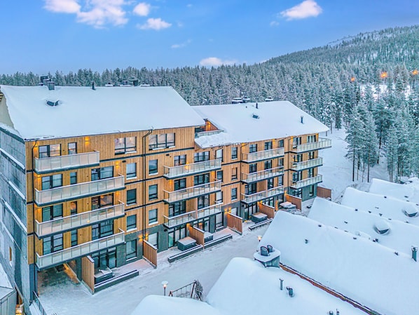 A multi-story hotel with balconies, located in a snowy mountainous area.