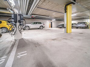 A multi-level parking garage with electric vehicle charging stations, concrete floors, and yellow pillars. - Villa valoki by Interhome (Kittilä)