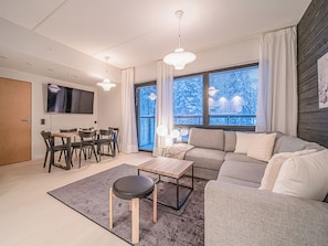 A modern living room with a sofa, coffee table, and dining area. - Villa valoki by Interhome (Kittilä)