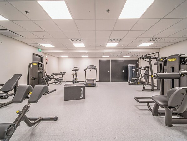 A gym with various exercise equipment, including treadmills, weight machines, and benches.
