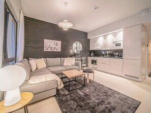 A modern living room with a grey sofa, a small wooden coffee table, and a black rug.