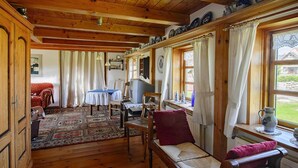 Um quarto aconchegante com vigas de madeira, uma mesa de jantar, um sofá e uma janela com cortinas.