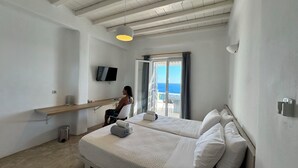 Ein Hotelzimmer mit Bett, Schreibtisch, Fernseher und Meerblick.