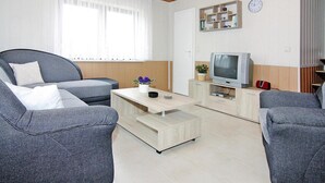 A modern living room with a grey sofa, a wooden coffee table, and a television on a wooden cabinet.