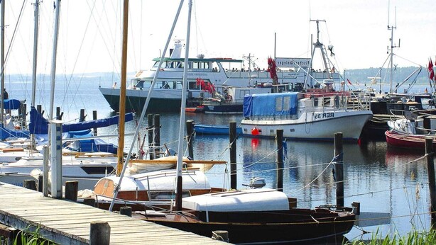 A marina with various boats docked, including a large fishing vessel and smaller boats.
