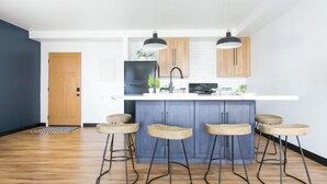 Een moderne keuken met een centraal kookeiland, barstoelen en hanglampen.