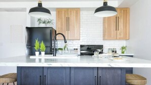 Een moderne keuken met een groot eiland, houten kastjes en barkrukken.