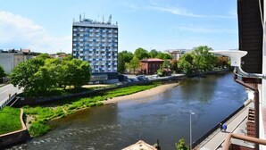 A river with a bridge, a tall building, and a red-roofed structure.