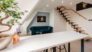 A modern interior with a white table, a potted plant, a blue sofa, and a staircase with wooden steps.