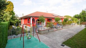 A red house with a swing set in the yard.