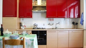 A compact kitchen with red cabinets, a black dishwasher, and a table set for dining.