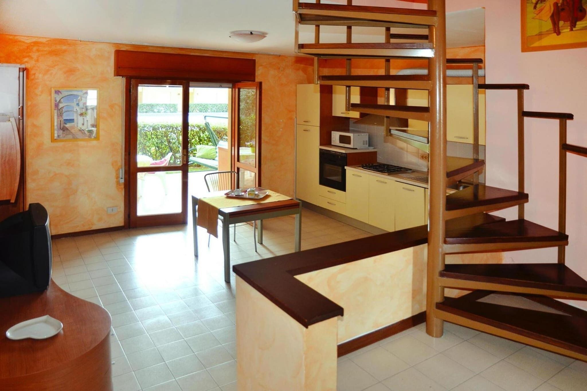 Un espace de vie compact comprenant une kitchenette, un coin repas et un escalier.