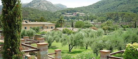 A villa with a garden, a mountain in the background, and a clear sky.