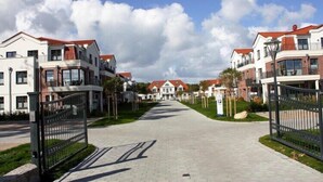Una calle residencial con casas modernas, una acera pavimentada y cielo despejado.