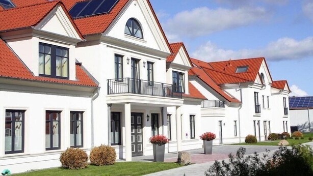Una hilera de casas blancas con tejados rojos y paneles solares.