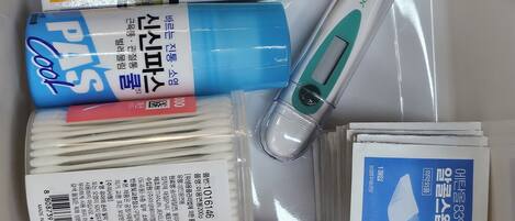 Diversos suministros médicos, incluyendo vendajes, un termómetro y una botella de ungüento.
