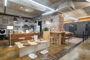 A modern interior with exposed brick walls, wooden furniture, and a central brick column. - Travel Light Hostel (Busan)