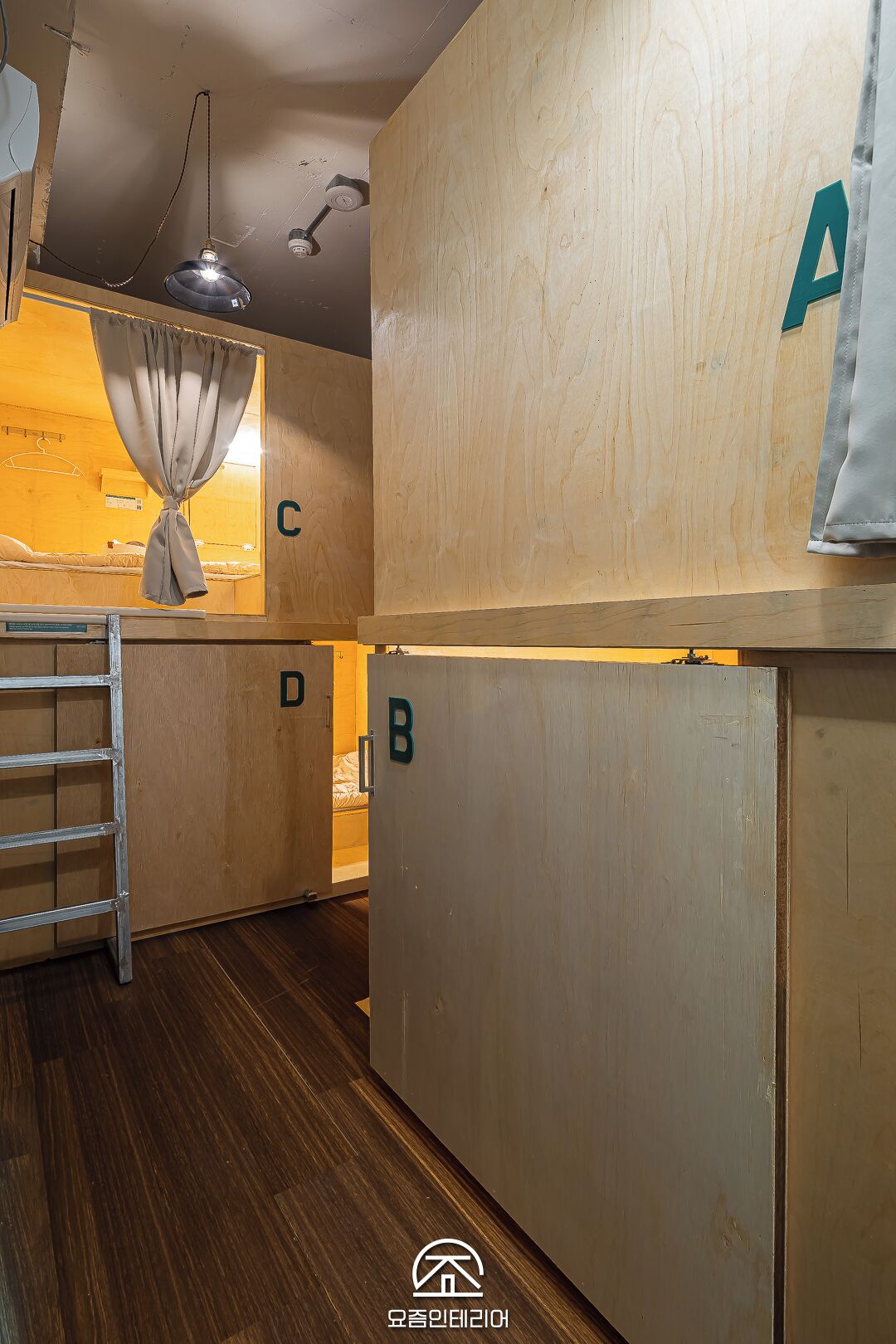 Habitación de hotel compacta con una litera, una escalera y una pequeña kitchenette.