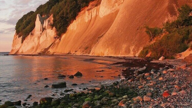 A coastal landscape with cliffs and a pebble beach.