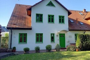 A two-story house with a green door, multiple windows, and a tiled roof. - Appartementhaus Kranichblick, Breege (Breege)