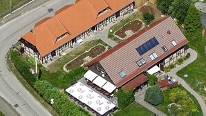Ein zweistöckiges Gebäude mit roten Ziegeldächern, einer überdachten Außenlounge und einer Solaranlage.