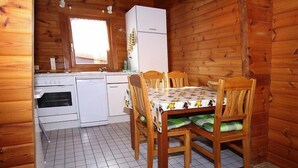 A compact kitchen with a dining table, wooden chairs, a refrigerator, and a window. - Blockhaus, Hasselfelde (Hasselfelde)