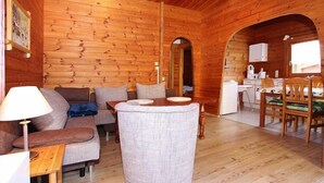 A cozy log cabin interior with a sofa, armchair, dining table, and a small kitchen area. - Blockhaus, Hasselfelde (Hasselfelde)