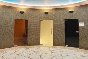 A lobby with three doors, a marble floor, and a textured wall.
