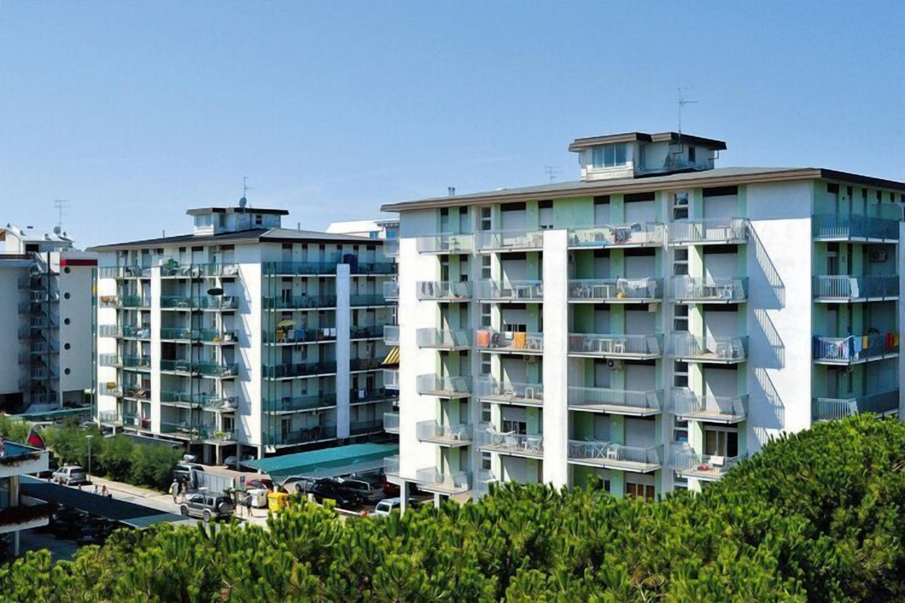 Un immeuble résidentiel à plusieurs étages, doté de balcons, d’un toit plat et surplombant un ciel dégagé.