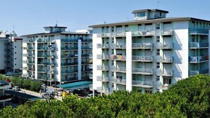 Un edificio residencial de varios pisos con balcones, techo plano y cielo despejado.