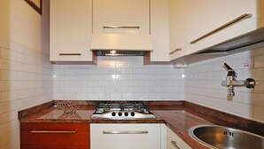 Una cocina con armarios blancos, un lavamanos de acero inoxidable y una estufa a gas.