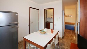 Una cocina compacta con refrigerador, una mesa de comedor con sillas y una pequeña encimera.