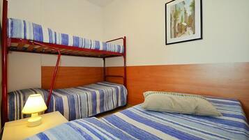 Un letto a castello con biancheria a righe, una lampada da comodino e un quadro appeso al muro.