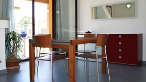 A modern dining area with a glass table, wooden chairs, and a red cabinet. - Apartment in Villaputzu with garden (Chia)