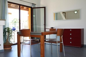 A dining area with a wooden table and chairs, a red cabinet, and a large window with a view of greenery. - Apartment in Villaputzu with garden (Chia)