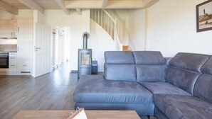 A modern living room with a grey sectional sofa, a wooden coffee table, and a fireplace. - Exklusiv eingerichtetes Ferienhaus in Strandnähe (Dagebüll)