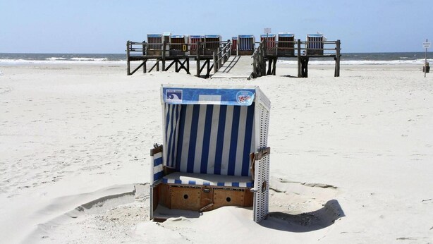 Une plage bordée de chaises longues et surmontée d’une tour de surveillance des sauveteurs.
