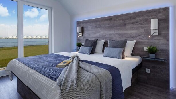 Een moderne slaapkamer met een groot bed, uitzicht op zee en een houten hoofdbord.