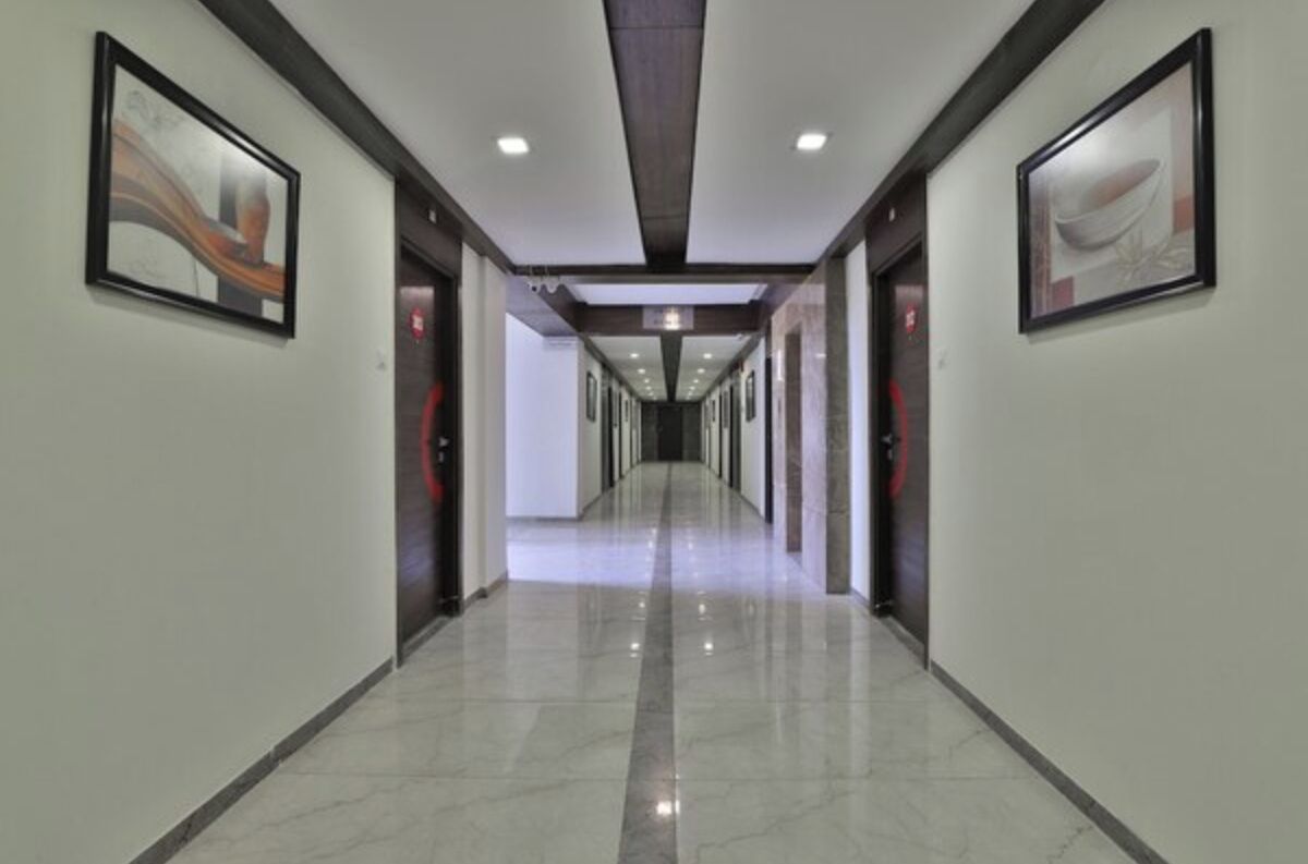 A modern hotel corridor with a straight path, framed artwork on the walls, and a polished floor.