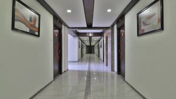 A modern hotel corridor with a straight path, framed artwork on the walls, and a polished floor.