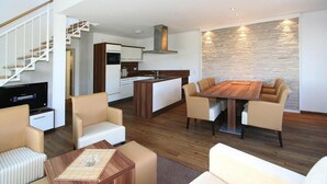 A modern living space with a dining area, kitchen, and a staircase.