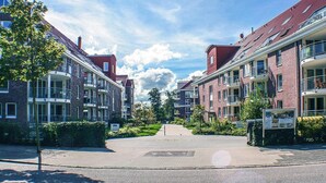 A residential street with brick apartment buildings, a central pathway, and a clear sky.