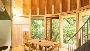 A wooden interior with a dining table and chairs, large windows, and a staircase. - Nordisk Hygge Circles UGAKEI (Inabe)