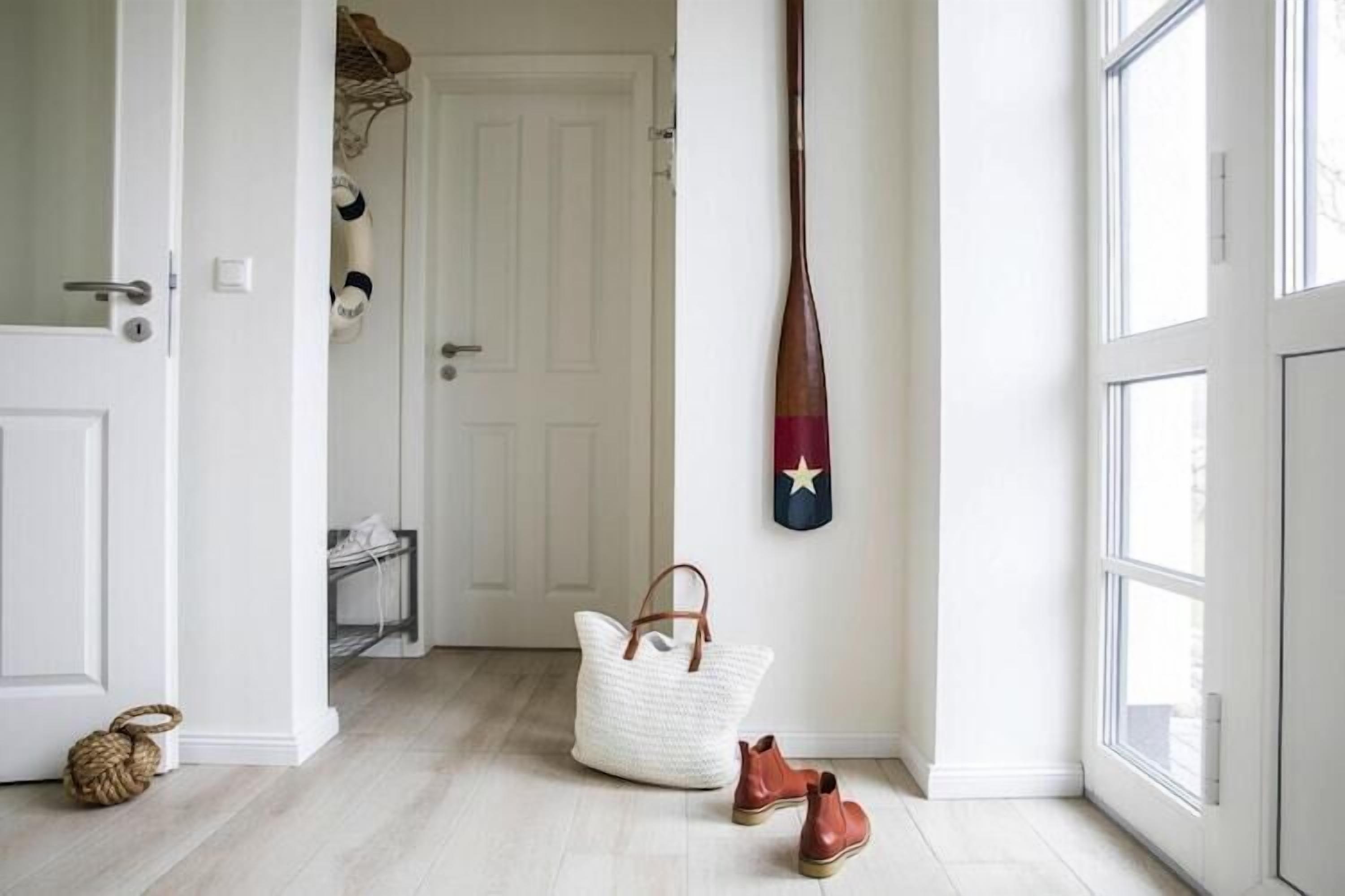 A hallway with a white door, a white woven bag, and a pair of brown shoes on the floor.